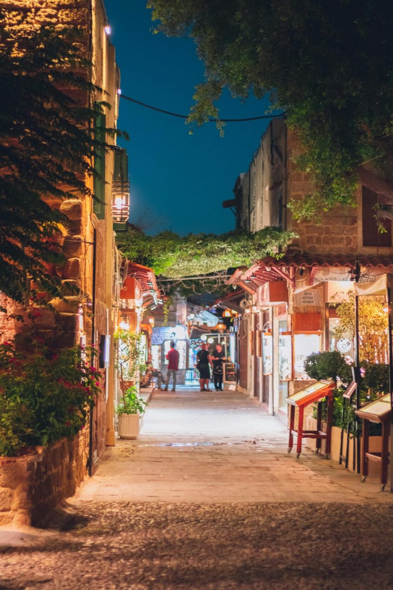 Enchanting night scene in Old Town Rhodes, Greece, with illuminated streets and inviting restaurants.