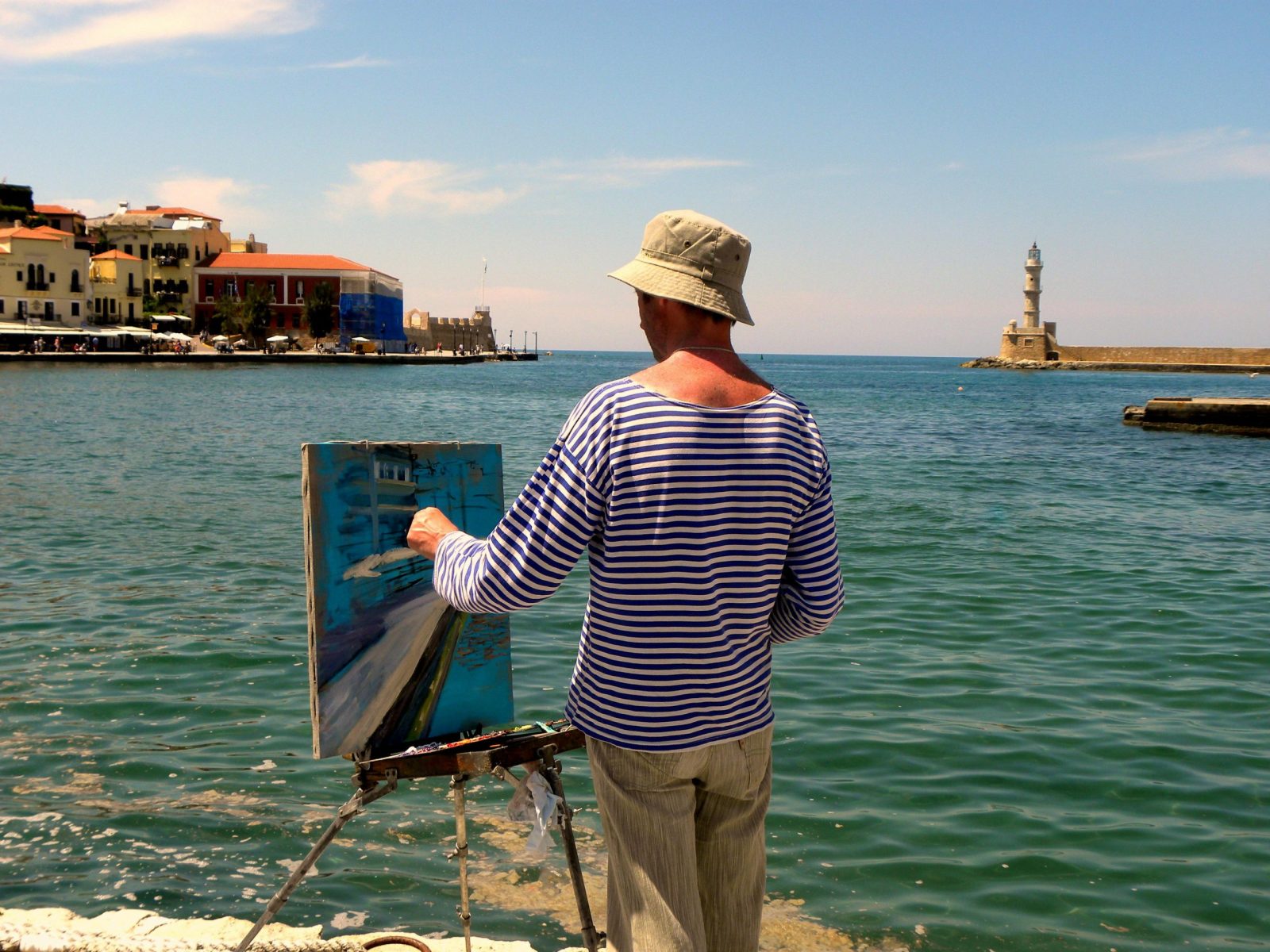 A painter capturing the scenic view of Chania lighthouse by the sea, Greece.